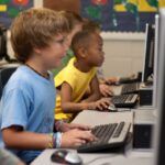 Students are engaged in learning, working on computers in a classroom setting.